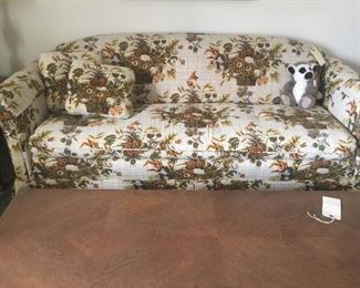 Go old school with this cool floral sofa. It’s sturdy, clean and ready for more life in a new home. In front of it sits a long coffee table with a shelf underneath and two doors to hold remotes and stash other stuff. 