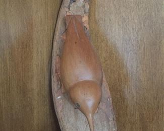 A darling, long-beaked carved bird is mounted on an interesting piece of wood. 