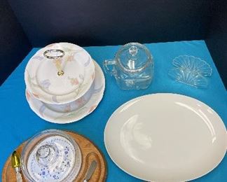 Party Serving Items. One cheese tray with 4 spreading knifes - One 2 teared serving dish - One large oval serving platter - One glass serving plate - One glass pitcher - One plastic clam shell design napkin holder.