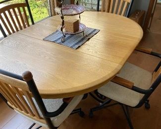 casual dining table on wrought iron base with single leaf 18", 40" without leaf and 42" wide with 4 upholstered chairs on casters