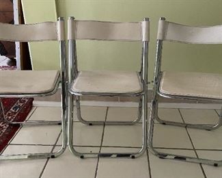 Trio of white leather and metal folding chairs