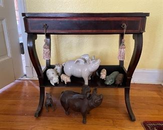 Display glass top wooden table with pull drawer, one shelf 
Collection of pig figurines in ceramic, stone and metal