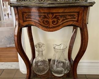 Wooden tall table with metal ornate details
Glass pitcher with stirir 
Glass collection of decanters  