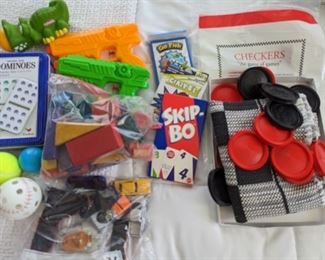 Lot of children's toys, checkers, domino's, cars, water guns, blocks, and card games.