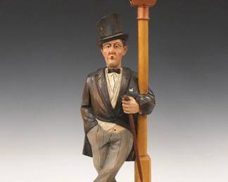 Lot 2: A mid 20th century German clockwork "Whistler" figure by Karl Griesbaum, Triberg.  Carved wooden automaton figure whose head moves and whistles a tune when activated via Brass key wind movement with bellows.  Original painted finish, with a battery operated street lamp.  Stamped "K G" Trademark with songbird.  Minor wear, working when cataloged.  18 3/4" high overall.  ESTIMATE $600-800

