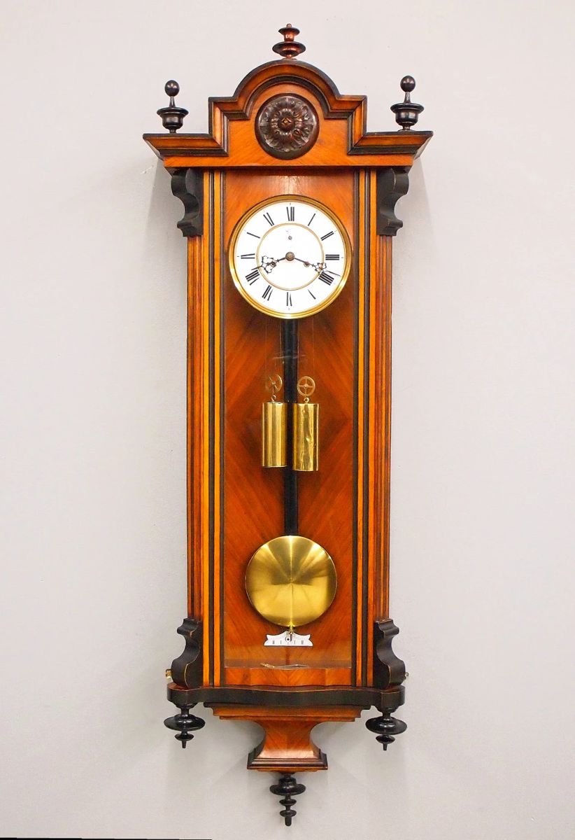 Lot 3: A late 19th century Vienna Regulator wall clock by H. Endler & Co. Freiburg, Germany.  8-day weight driven time only movement with two part porcelain dial with Roman numerals, subsidiary seconds and molded Brass bezel, serial #101468.  Figured Walnut Biedermeier case with a stepped, arched crown and turned finials over a single long door with arched glass flanked by fluted pilasters with shaped detail over a shaped drop.  Older finish with Ebonized detail, minor wear, replaced top finial, running when cataloged.  47 1/2" high overall.  ESTIMATE $400-600
