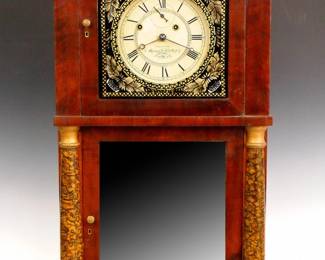 Lot 4: A 19th century Munger & Benedict Empire Period shelf clock.  8-day weight driven Brass time and strike movement (marked No. 98 on front plate), papered dial with Roman numerals and "Flying Eagle" pendulum, marked "Warranted by, Munger & Benedict, Auburn, N.Y.".  Mahogany case with carved Eagle crest above an upper dial door with reverse painted glass and a lower mirrored door, flanked by painted pilasters over carved paw feet, with original wall paper on backboard.  Older refinishing with minor damage, dial wear and edge damage, restored crest, running when cataloged.  39 3/4" high overall.  ESTIMATE $600-800
