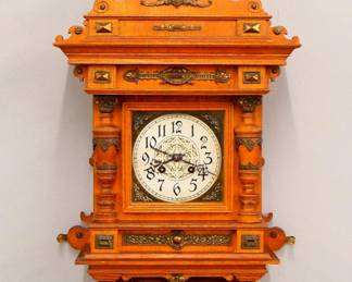 Lot 10: A turn of the century Lenzkirch No. 71 "Peacock" model Freischwinger wall clock.  8-day spring driven time and strike movement with Brass dial and engraved Silvered chapter ring, Arabic numerals and fancy cast Brass pendulum, serial #1 Million 143274 indicates a production date of 1905.  Oak case with applied Brass detail and fancy crest, dial door with turned pilasters and shaped bracket drop.  Old finish with some wear, running when cataloged.  40" high overall.  ESTIMATE $800-1,200
