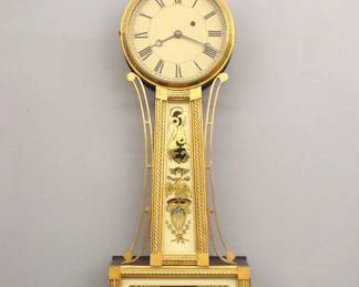Lot 42: A mid 19th century American Banjo clock, attributed to George D. Hatch, North Attleboro, Mass.  8-day time only movement with painted Iron dial and Roman numerals.  Mahogany case with a Brass finial over a molded Brass dial door, tapered throat panel with applied rope moldings and reverse painted glass flanked by shaped Brass side arms, lower door with a reverse painted interior scene glass by Tom Moberg.  Older finish with some wear, dial restored, restored lower glass, replaced finial, running when cataloged.  35" high overall.  ESTIMATE $2,000-3,000
