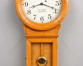 Lot 43: A turn of the century Chelsea No. 1 Pendulum model wall clock.  From the jewelry store of "Wm. D. Ward, Hyde Park, Mass" (on dial) additionally retains Ward's paper label inside lower door.  8-day weight driven time only movement with painted metal dial and Arabic numerals, serial #110477.  Oak case with circular upper dial door, rectangular lower door and short molded drop.  Original light Oak finish with minor wear, slight dial wear, running when cataloged.  34" high overall.  ESTIMATE $1,000-1,500
