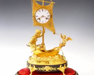 Lot 52: A late 19th century French Bronze figural clock depicting Venus & Amor.  8-day time and strike movement with silk thread suspension, convex porcelain dial, Roman numerals and Gilded filigree hands by Japy Freres, retailed by "Kottot a Paris", serial #1426.  Bronze case with Gilded and dark Brown patina depicts Venus seated in a sailboat with a winged Cherub at the stern below a sail with inset clock movement, on an oval base with winged Lion feet, under a glass dome with a Black Slate oval base and turned Brass feet.  Minor wear, very good overall condition, running when cataloged.  Clock only is 17 1/2" high, 21 3/4" high overall with dome.  ESTIMATE $2,000-3,000
