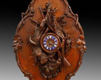 Lot 58: A late 19th century Black Forest wall clock.  8-day time and strike movement by Japy Freres & Cie, wooden dial with porcelain hour markers and Roman numerals, serial #3512.   Hand carved Walnut case with hanging game, hunting horn, rifle and various hunting accoutrements on a shaped plaque with carved branches and foliage.  Original finish with good color, minor wear and small edge repairs, running when cataloged.  31" high x 20" wide overall.  ESTIMATE $3,000-4,000
