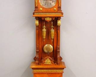 Lot 60: A 19th century Lenzkirch Grandfather clock.  8-day weight driven time and strike movement with engraved Silvered dial and Arabic numeral and etched "Owl" pendulum, serial #723541 indicates a production date of 1886.  Oak open well design with cast Brass appliques and moldings, features a stepped arched top with turned and tapered finials over a molded cornice and upper door with circular dial glass and flat tapered pilasters over and open well with paneled back and scrolled brackets, on a base section with Brass Lion's mask on a carved panel and turned feet.  Older finish with slight wear, running when cataloged.  99" high overall.  ESTIMATE $3,000-4,000

