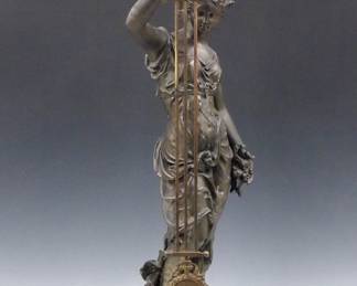 Lot 61: A 19th century French figural Swinging Arm clock by Andre Romain Guilmet, Paris.  8-day time only movement within a nickeled cannister form body with porcelain dial, Roman hour and Arabic minute numerals with gridiron pendulum and Gilded mounts, rear plate with "G L T" trademark, serial #9494.  Dial marked with the Retailer's information "Comptoir General, 9 Boul'd Poissonniere, Paris".   Allegorical "Spring" Spelter figure with dark Green patina and Ebonized turned wooded plinth.  Some wear to the original finish, running when cataloged.  35 1/2" high overall.  ESTIMATE $3,000-4,000 
