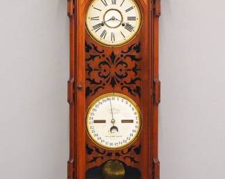 Lot 64: A late 19th century Ithaca "Vienna No. 3" model Calendar wall clock.  30-day dual spring time only movement with papered metal dial and Roman numerals, lower calendar mechanism with papered dial and rollers.  Walnut case with carved crest over a single long molded door with filigree baffle, turned drop finials and shaped lower drop.  Older finish with minor wear, replaced drop, one repaired finial, running when cataloged.  51 1/2" high overall.  ESTIMATE $3,000-4,000
