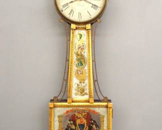 Lot 67: A mid 19th century American Presentation Banjo clock.  8-day time only movement with painted Iron dial and Roman numerals signed "G. G. Brewster, Portsmouth".  Mahogany case with Gilded front, turned Gilded finial over a molded Brass dial door, tapered throat panel with applied rope moldings and reverse painted glass flanked by shaped Brass side arms, lower door with a reverse painted Naval Battle scene labeled "Constitution & Guerriere, Hull" above a shaped drop with carved detail.  Old finish with some wear, dial wear and craquelure, minor flaking to glasses, running when cataloged.  39" high overall.  ESTIMATE $3,000-4,000
