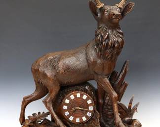 74: A late 19th century Black Forest figural clock.  8-day Brass time and strike movement marked "Leuenberger, Interlaken, 1359" with a carved wooden dial and applied Roman numerals on porcelain plaques.  Hand carved case with a full bodied Red Stag standing on a forest floor, fitted with Stag horns.  Original dark finish with some wear and minor damage, running when cataloged.  32 1/4" high overall.  ESTIMATE $4,000-6,000

