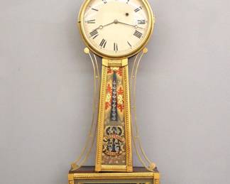 Lot 93: A mid 19th century American Banjo clock.  8-day time only movement with painted Iron dial and Roman numerals.  Mahogany case with a Brass Eagle finial over a molded Brass dial door, tapered throat panel with applied rope moldings and reverse painted glass marked "Warranted, Patent" flanked by shaped Brass side arms, lower door with a reverse painted "Aurora" glass.  Older finish with some wear, some dial wear, restored lower glass, running when cataloged.  34" high.  ESTIMATE $1,500-2,000
