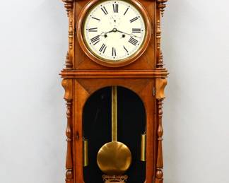 107: A 19th century E. N. Welch "No. 5 Regulator" model wall clock.  8-day dual weight time only movement with painted metal dial with Roman numerals and subsidiary seconds, original Gilded pendulum rod.  Walnut case with a shaped crest, circular upper door over an arched lower door and shaped drop.  Older refinishing with minor, replaced lower finials one with small chip at tip, minor dial imperfections, running when cataloged.  51" high overall.  ESTIMATE $1,000-1,500
