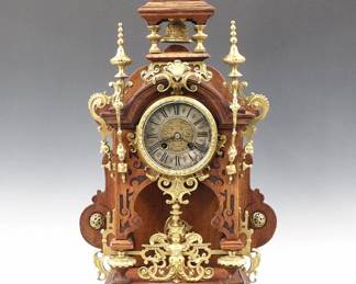 Lot 109: A late 19th century Lenzkirch table clock.  8-day spring driven time and strike movement with engraved Brass dial center, Silvered chapter ring and Roman numerals, serial #811896 indicates a production date of 1888.  Oak case with open well, cast Brass finials and appliques, molded circular Brass dial door flanked by Brass corbels, on a molded base with Brass Dolphin feet.  Older finish with minor wear, running when cataloged.  24" high overall.  ESTIMATE $800-1,200
