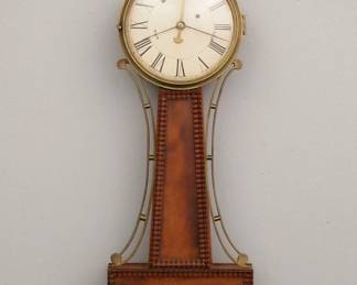 Lot 108: An early 19th century American Banjo clock with alarm.  8-day Brass, weight driven time movement with spring driven alarm, exterior top mounted alarm bell, painted Iron dial with Roman numerals.  Mahogany case with pierced Brass arms, Brass dial door with convex glass over Mahogany throat and lower door panels with applied Ripple moldings.  Older finish with wear, replaced Eagle finial, running momentarily when cataloged.  33" high overall.  ESTIMATE $1,000-2,000
