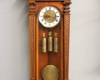 Lot 129:  A 19th century Vienna Regulator wall clock.  8-day weight driven time and strike movement with Grand Sonnerie quarter hour chime, engraved Brass dial porcelain chapter ring and Roman numerals, engraved weights and pendulum, serial #97758.  Walnut case with arched crest and turned finial over a long door with carved tapered pilasters and shaped lower drop.  Older finish with slight wear, running when cataloged.  51 1/2" high overall.  ESTIMATE $800-1,200
