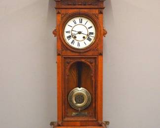 Lot 130:  A 19th century Lenzkirch wall clock.  Series 24, 8-day spring driven time and strike movement with two part porcelain dial and Roman numerals and fancy etched Silvered pendulum, serial #86198 indicates a production date of 1863.  Oak case with carved decoration, arched crest over molded crown and single door with circular dial glass and arched lower, tapered lower bracket drop.  Older refinishing with minor wear, some shrinkage, multiple dial hairlines, replaced bottom finial, running when cataloged.  42" high overall.  ESTIMATE $800-1,200
