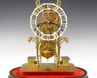 Lot 141: A 20th century English Brass Skeleton clock.&nbsp; 8-day Fusee driven movement with Brass cut out dial with Roman numerals.  Brass Gothic Style plates with turned posts on a molded Ebonized wooden base with glass dome.&nbsp; Minor wear, replaced dome, running when cataloged.  17" high overall.&nbsp; ESTIMATE $600-800
