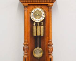 Lot 143: A late 19th century Gustav Becker wall clock by Kienzle, Schwenningen, Germany.  8-day weight driven time and strike movement with quarter hour Grand Sonnerie chime and two part Brass/Silvered dial with Roman numerals and molded Brass bezel, etched dial center, weights and pendulum, serial #531.  Altdeutsch Style Walnut case with carved crest over a single long door with arched glass flanked by fluted pilasters with carved detail over a shaped drop.  Older refinishing with minor wear, running when cataloged.  49 1/2" high overall.  ESTIMATE $600-800
