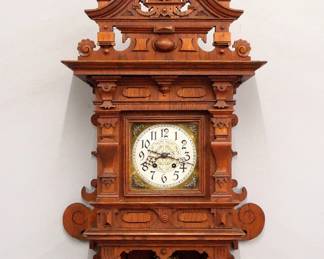 Lot 155: A late 19th century Lenzkirch Freischwinger wall clock.  Series 26, 8-day spring driven time and strike movement with Brass dial, cast spandrels and engraved Silvered center, Arabic numerals and fancy cast Brass pendulum, serial #1 Million 190746 indicates a production date of 1898.  Oak case with pierced arched crest over a square dial door with shaped pilasters and lower shaped bracket drop.  Old finish with some wear, running when cataloged.  40" high overall.  ESTIMATE $600-800
