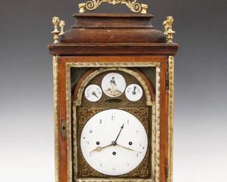 Lot 156: An 18th century German Bracket clock attributed to Fidelis Meyer.  8-day spring driven time and strike movement with quarter hour Grand Sonnerie striking on two bells, Crown wheel escapement, Calendar hand, convex porcelain dial with Arabic numerals, false pendulum aperture, subsidiary Repeat/Silent dials and cast spandrels.  Walnut case with Gilded cast Brass handle and finials on an inverted bell form top, single door with applied Gilded moldings on cast Brass feet.  Older finials with wear and repairs, dial hairlines, running when cataloged.  23" high overall.  ESTIMATE $600-800 
