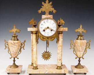 Lot 161:  A turn of the century French three piece clock set.  8-day time and strike movement marked "Selsi, Paris" with convex porcelain dial with Arabic numerals and floral swags.  Louis XVI Style Bronze mounted Marble case with four turned Marble columns and two matching garnitures.  Some wear, clock running when cataloged.  16" high overall.  ESTIMATE $600-800
