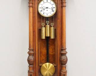 Lot 164: A late 19th century Vienna Regulator wall clock.  8-day weight driven time and strike movement with quarter hour Grand Sonnerie chime and two part porcelain dial with Roman numerals and molded Brass bezel.  Altdeutsch style Walnut case with and arched crest over a single long door with arched glass flanked by fluted pilasters with carved detail over a shaped drop.  Older finish with some wear and minor damage, replaced finials, dial hairlines, running when cataloged.  54" high overall.  ESTIMATE $600-800
