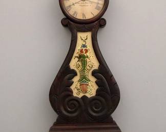 Lot 171:  A late 20th century American Lyre front Banjo clock by "Kilbourn & Proctor, Waltham".  8 day weight driven time only movement with a painted Iron dial and Roman numerals.  Mahogany case with carved foliate top finial over a circular dial door with convex glass and carved foliate throat panel with reverse painted glass, shaped drop with beaded detail and turned bottom finial.  Some case wear, dial antiqued, running when cataloged.  39 1/2" high overall.  ESTIMATE $600-800
