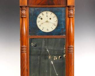 Lot 176: A 19th century Asa Munger shelf clock with "Ironing Board" top.  8-day Brass time and strike movement with painted metal dial, Roman numerals, subsidiary seconds and original Iron hands with "Auburn Patent" Pewter pulleys and "Flying Eagle" pendulum bob.  Mahogany case with shaped, reeded top, single long door with applied pilasters and metal backed glass upper panel and mirrored lower panel.  Paper label 80% intact.  Older refinishing with some wear, damage to the silvering on mirror, runs momentarily when cataloged.  40 1/4" high overall.  ESTIMATE $600-800

