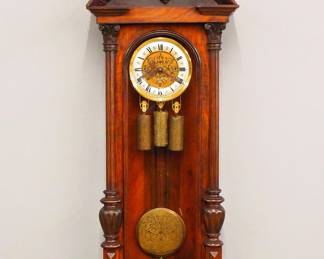 Lot 179:  A late 19th century Vienna Regulator wall clock by Gustav Becker.  8-day weight driven time and strike movement with quarter hour Grand Sonnerie chime and two part Brass/Silvered dial with Roman numerals and molded Brass bezel, etched dial center, weights and pendulum, serial #161796.  Altdeutsch style Walnut case with carved crest over a single long door with arched glass flanked by fluted pilasters with carved detail over a shaped drop.  Older finish with some wear and minor damage, running when cataloged.  50" high overall.  ESTIMATE $600-800
