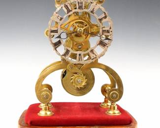 Lot 203: An early 20th century English Skeleton clock.  8-day time only fusee movement with Silvered filigree dial and Roman numerals.  Shaped Brass plates with turned posts, on a molded wooden base.  Minor wear, dial wear, lacks glass dome, running when cataloged.  11 3/4" high overall.  ESTIMATE $300-500
