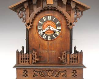 Lot 202:  A 19th century Black Forest table top Cuckoo clock by Gordian Hettich & Sohn, Furtwangen, Germany.  8-day time and strike movement with Brass cutout plates, marked "G. H. S. 13", shield form pendulum, carved dial and applied bone hands and Roman numerals.  Oak Gothic Revival Period case with extensive carved detail including an arched crest above a dial surround with carved tracery flanked by rope twist columns on a stepped base with molded feet.  Older finish with some wear, lacks roof trim and some applied detail, replaced Cuckoo door, running when cataloged.  18 3/4" high overall.  ESTIMATE $400-600
