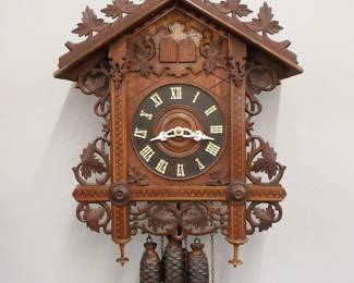 Lot 204: An early 20th century German Black Forest Railway Cuckoo wall clock.  30-hr three weight movement with Brass cutout plates, Cuckoo and Quail chime at the hour and quarters, turned wooden dial with applied Roman numerals.  Carved Walnut case features a foliate crest, above and inlaid dial frame and scrolled foliate detail with turned finials.  Some surface wear, restored crest, running when catalogued.  31" high plus weight drop.  ESTIMATE $300-500
