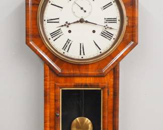 Lot 215: A late 19th century E. N. Welch "Verdi" model Schoolhouse clock.  8-day time and strike movement with painted metal dial and Roman numerals, subsidiary seconds.  Rosewood long drop case with octagon top and molded lower door with Gilded liner.  Paper label verso 90%.  Older refinishing, some wear, minor dial wear, running when cataloged.  31 1/2" high overall.  ESTIMATE $300-400
