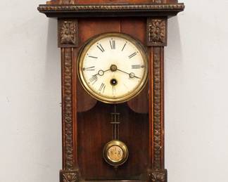 Lot 239: A turn of the century Junghans miniature wall clock.  30-hr spring driven time only movement with painted metal dial, Roman numerals and R/A pendulum.  Mixed wood case with applied composition detail features an arched crest over a single door with arched glass, and a shaped lower drop.  Old dark finish with wear, top finial with damage, running when cataloged.  22 1/2" high overall.  ESTIMATE $200-300
