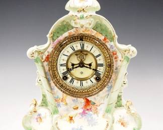Lot 238:  A turn of the century Ansonia "No. 502" model China shelf clock.  8-day time and strike movement with visible escapement, a two-part porcelain dial and Roman numerals.  Royal Bonn porcelain case with floral decoration and Gilded detail.  Some wear and crazing, running when cataloged.  13 1/2" high overall.  ESTIMATE $200-300
