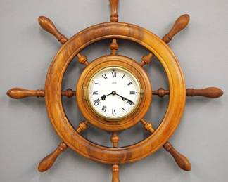Lot 240: A late 20th century Schatz Ship's Wheel wall clock.  8-day time and strike movement with Ship's strike, papered metal dial and Roman numerals, hinged molded Brass bezel.  Walnut Ship's Wheel frame with turned posts.  Minor wear, fading to finish, running when cataloged.  24 1/2" diameter.  ESTIMATE $200-300  

