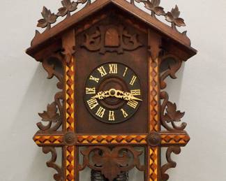 Lot 244: An early 20th century German Black Forest Railway Cuckoo wall clock.  30-hr two weight movement with Brass cutout plates, Cuckoo chime at the hour and quarters, turned wooden dial with applied Roman numerals.  Carved Walnut case features a foliate crest, above and inlaid dial frame and scrolled foliate detail with turned finials.  Some surface wear, restored crest and finials, not running when catalogued.  22" high plus weight drop.  ESTIMATE $200-300
