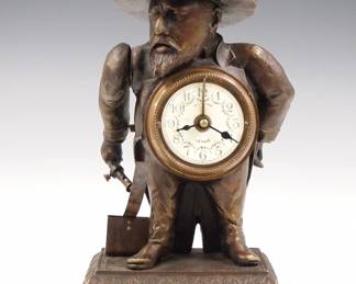 Lot 246: A reproduction French Automaton novelty clock.  30-hr movement with alarm, a match in the figure's hand strikes and lights a candle in the hat when activated.  Bronze figural case with a molded base.  Slight wear, running when cataloged.  9" high overall.  ESTIMATE $200-300
