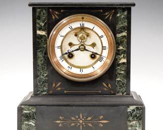 Lot 254: A turn of the century French Marble mantel clock.  8-day time and strike movement with visible escapement, two part porcelain dial and Roman numerals.  Black Marble case with Verde accents and Gilded detail features a flat top and molded base.  Some wear, cracks in Marble, running when cataloged.  8 3/4" high overall.  ESTIMATE $100-150
