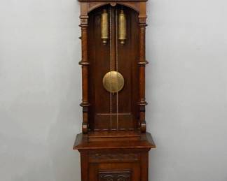 Lot 97: A late 19th/early 20th century Grandfather clock by Kienzle, Schwenningen, Germany.  8-day weight driven time and strike movement with engraved Brass dial with Silvered chapter ring and Arabic numeral, etched weights and pendulum with Art Nouveau influence, retailed by "Luppe & Heilbronner, Munich" on dial center, serial #7385.  Arts and Crafts Period Oak open well design features a stepped molded cornice over a carved frieze and upper door with circular dial glass with molded frame over and open well with paneled back, turned columns and scrolled brackets, on a base section with carved foliate panel and shaped bracket feet.  Original dark finish with slight wear, running when cataloged.  80 1/2" high overall.  ESTIMATE $2,000-3,000
