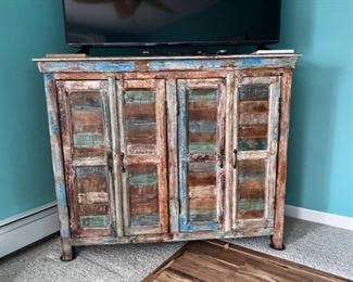 Distressed wood cabinet. Two sets of doors, shelves.