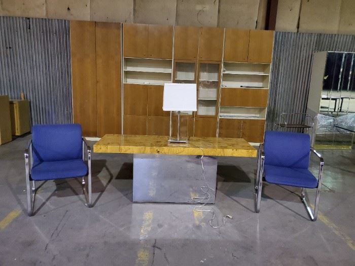 Front and center is a Milo Baughman for Thayer Coggin console table with solid glass and chrome contemporary lamp, flanked by a pair of chairs by Peter Protzman for Herman Miller and dominating the backdrop is a massive German Teak front wall unit.