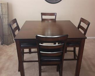 Dark Wood Counter Table with Four Padded Cushion Seats.  Measures 42"x42"x35.5" tall.  Excellent condition.
